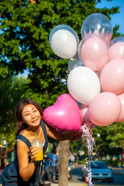 young asian beautiful woman with flying multicolored balloons in the city.