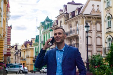 Kendinden emin genç işadamı şehirde cep telefonu kullanıyor. 