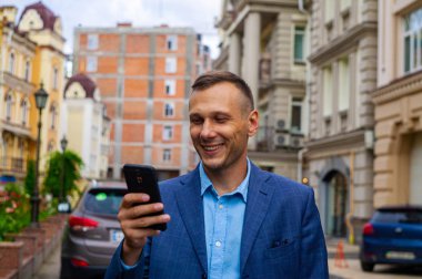 Şehirde telefon kullanarak gülümseyen yakışıklı işadamı.