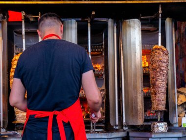 Büyük bıçaklı bir adam yürüyen caddede bir Doner Shawarma pişiriyor..