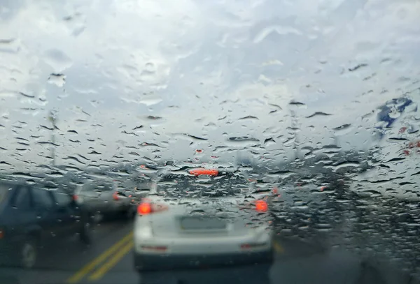 Rain drop on the car glass background.Road view through car window with rain drops, Driving in rain.Abstract traffic in raining day. View from car seat.