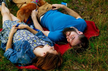 Selfie çekiyorum. Güzel iyi çekici gülümseyen mutlu contended genç-yetişkin çift beyaz sevimli köpek ile çim üzerinde vakit geçirmek ve selfie alarak.