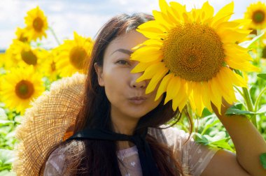 Ayçiçeği alanında hasır şapka ile Mutlu güzel asya kadın.