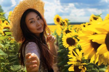 Ayçiçeği alanında hasır şapka ile Mutlu güzel asya kadın.