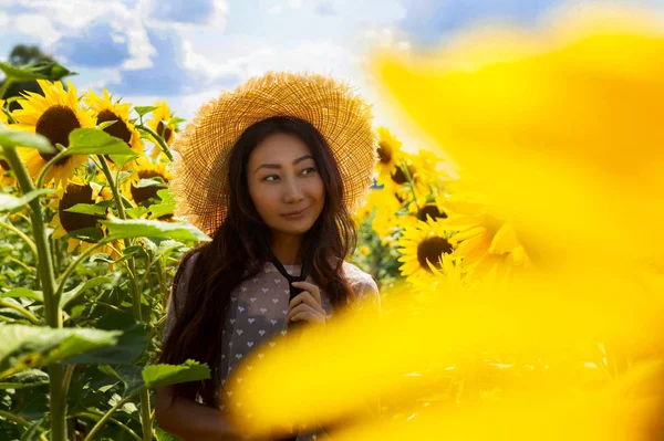Ayçiçeği alanında hasır şapka ile Mutlu güzel asya kadın.