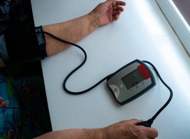 evde yaşlı bir kadın kan basıncını ölçmek için cihaz hazırlar.