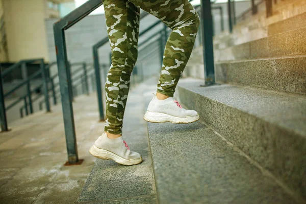 Close up of young woman sporty legs preparing to run upstairs on her everyday urban workout. Healthy lifestyle concept