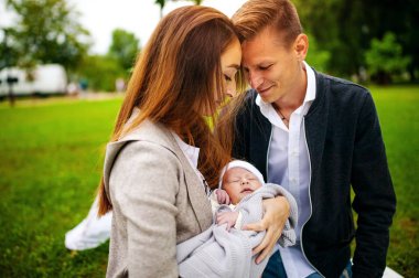 Genç aile ve yeni doğan oğlu sonbahar Park kamera için poz.