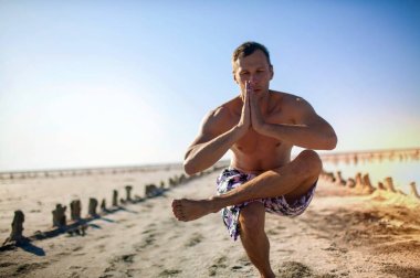 Fit genç adam alacakaranlıkta dramatik bir gökyüzüne karşı dua elleriyle ayakta iken onun yoga uygulaması sırasında meditasyon.