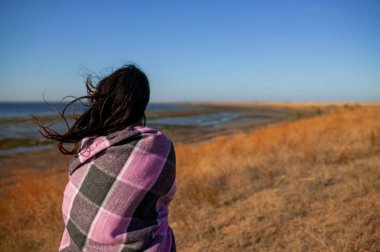 genç koyu saçlı kadın gün batımında deniz kıyısında duran ve hayat hakkında düşünme.