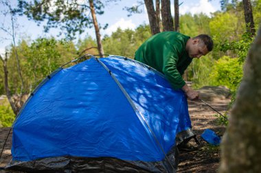 Bir adam, ormanın içindeki gelecek kampına çadır kuruyor.