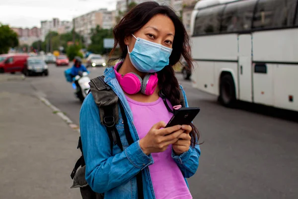 Chinese Woman Waiting For Bus At Bus Stop In City Street And Wearing Face Mask