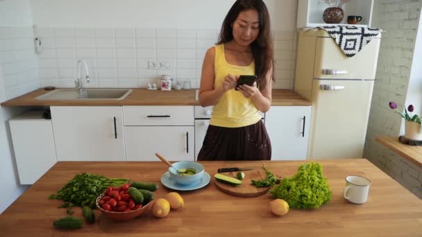 Mujer Asiática Sonriente Usando Smartphone Para Buscar Recetas Ensalada Cocina — Vídeos de Stock