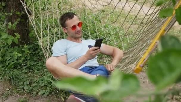 Jeune Homme Détendu Regardant Téléphone Portable Dans Hamac — Video