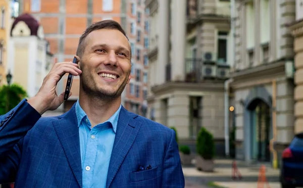 Smiling Business Man Talking On Mobile Phone In The City