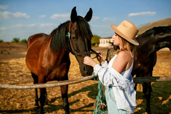 一个小女孩站在农场的一群马旁边 — 图库照片