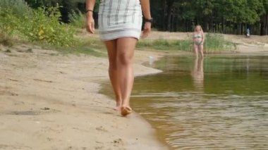 İnce kadın bacakları göl ya da nehir boyunca yürüyor.
