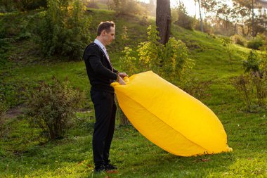 Genç bir kadın sarı bir Lamzac 'ı havayla şişiriyor. Bir kadın parkta bir koltuğu şişiriyor.. 