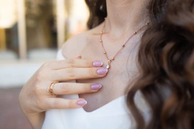 Elinde altın kolye ve minimalist yüzüklerle zarif bir genç kadının kırpılmış görüntüsü. Mücevher, lüks, aksesuar kavramı.