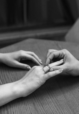 Bir gelin ve damat evleniyor ve yüzükleri değiş tokuş ediyorlar. Gelinin eli damadın parmağına yüzük takıyor..