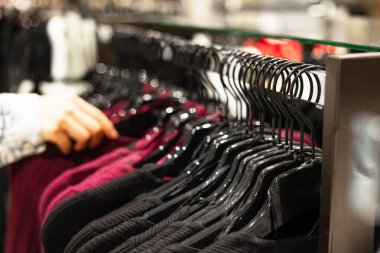 Kadın eli bitli genç ve indirimli tişörtleri mağazada seçerken, bit pazarındaki askılarda ucuz süveter ararken veya alırken, alışveriş giyim mağazasındaki moda konseptini geciktirirken..