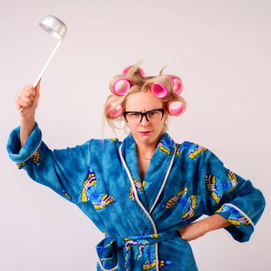 Bir sabahlık ve curlers sert bir kadında bir kepçe salıncaklar.