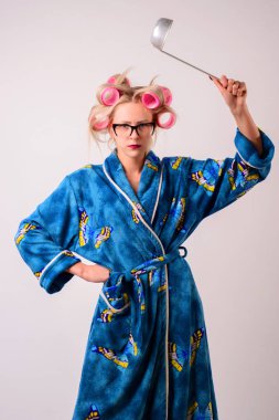 Bir sabahlık ve saç curlers memnun kadında bir kepçe salıncaklar.