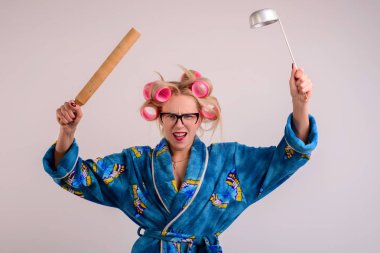 onun elinde bir kepçe ile bir sabahlık ve curlers kızgın ev kadını.