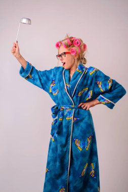Onun elinde bir kepçe ile bir sabahlık ve curlers çılgın ev kadını çığlık