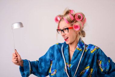 Onun elinde bir kepçe ile bir sabahlık ve curlers çılgın ev kadını çığlık.