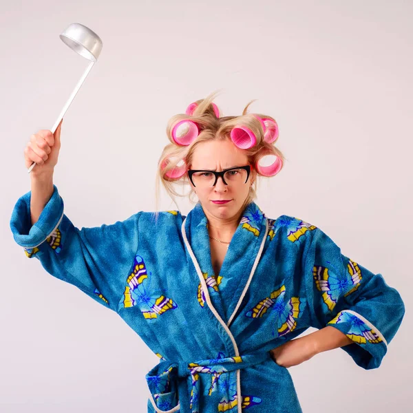 Bir sabahlık ve curlers sert bir kadında bir kepçe salıncaklar.