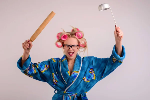 angry housewife in a dressing gown and curlers with a ladle in her hand.