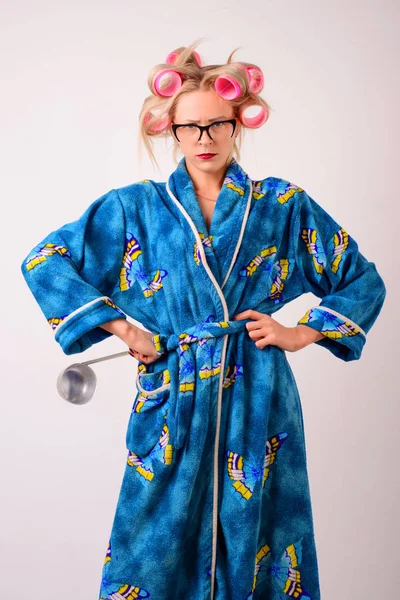 Onun elinde bir kepçe ile bir sabahlık ve curlers memnun ev kadını.