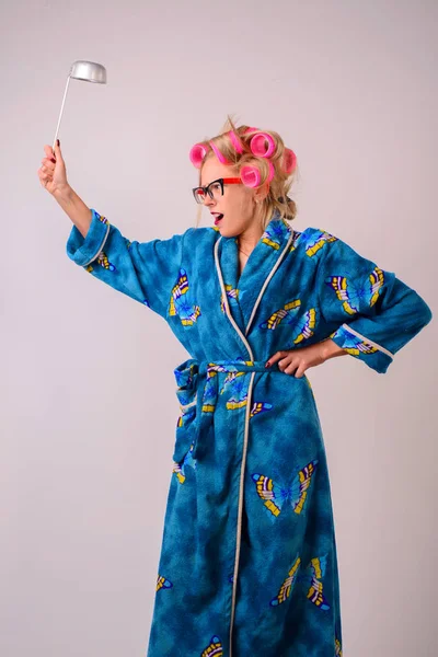 Onun elinde bir kepçe ile bir sabahlık ve curlers çılgın ev kadını çığlık