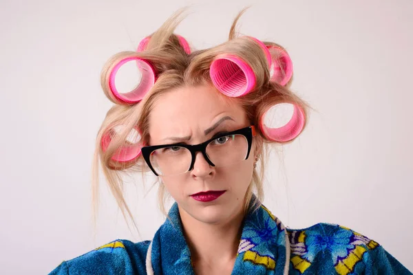 Yakın çekim portre ev kadını bir bornoz ve curlers içinde. Kameraya bir kaş kaldırdı arıyorsunuz