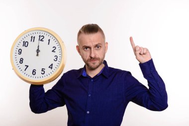 Sıkı adam büyük duvar saati tutan ve bir parmak üstünde boş yer üstünde beyaz arka plan puan