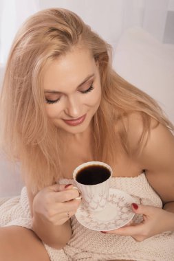 Genç kadın coffie, bir fincan ile yatakta otururken yukarıdan görüntülemek.