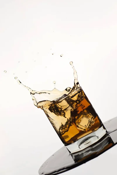 Nakloněné Sklenice Stříkající Whisky Ledem Izolované Bílém — Stock fotografie