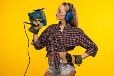 Sarı arka plan - görüntü önünde bir testere ile genç craftswoman