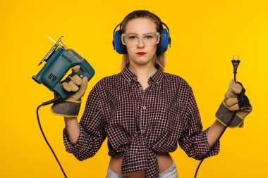 Sarı arka plan - görüntü önünde bir testere ile genç craftswoman