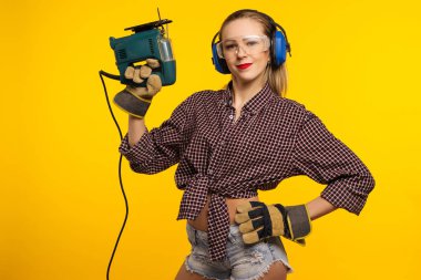 Sarı arka plan - görüntü önünde bir testere ile genç craftswoman