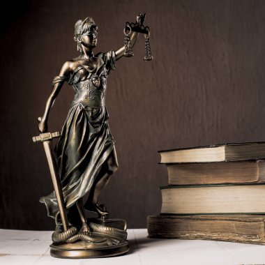 Beyaz ahşap bir masa yanında bir yığın üzerinde Themis heykelcik duruyor eski kitaplar. Terazi hukuk avukat iş kavramı. -Görüntü