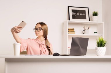 Cep telefonu ile selfie dizüstü bilgisayar - görüntü ile otururken alarak oynak bir genç kız portresi