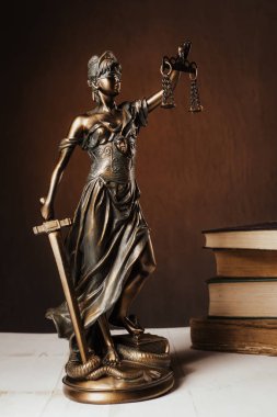 Beyaz ahşap bir masa yanında bir yığın üzerinde Themis heykelcik duruyor eski kitaplar. Terazi hukuk avukat iş kavramı. -Görüntü
