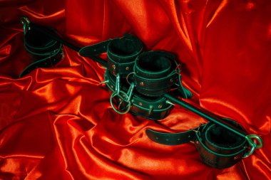 BDSM kıyafet kadar kapatın. Esaret, garip yetişkin seksi oyunlar, ilginçlik ve Bdsm yaşam tarzı konsepti ile bir çift deri kelepçe, flogger, kırmızı ipek kopya alanı ile bağlı bir kira kontratı.