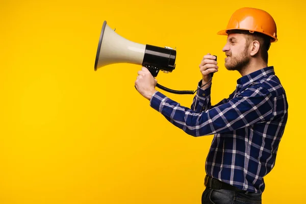 Trabalhador irritado homem com um megafone no fundo amarelo — Fotografia de Stock