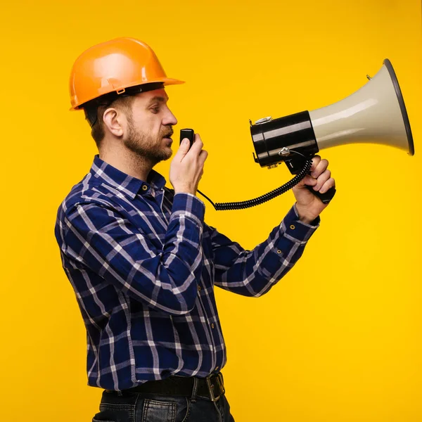 Trabalhador irritado homem com um megafone no fundo amarelo — Fotografia de Stock