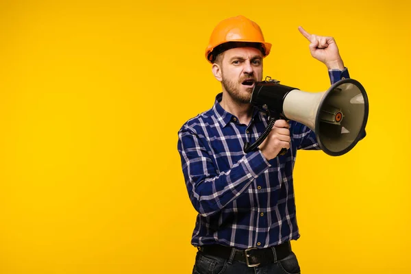 Angry worker man with a megaphone on yellow background