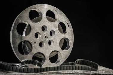 35 mm film reel with dramatic lighting on a dark background clipart