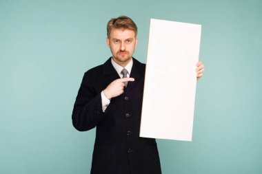 Mutlu gülümseyen genç iş adamı noktaları parmak boş tabela